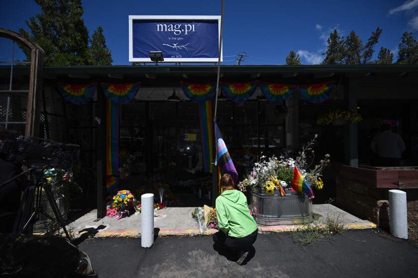 A resident leaves flowers at a makeshift memorial outside the Mag.Pi clothing store in Cedar Glen, near Lake Arrowhead, California, on August 21, 2023. The owner of the store, Laura Ann Carleton, was fatally shot on August 18 by a man who "made several disparaging remarks about a rainbow flag" displayed outside her store, according to the San Bernardino County Sheriff's department. The suspect was later killed during an encounter with deputies. (Photo by Robyn Beck / AFP) (Photo by ROBYN BECK/AFP via Getty Images)