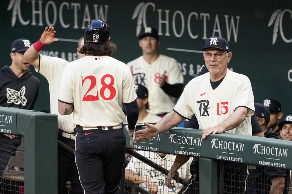 Texas Rangers' Jonah Heim (28) and manager Bruce Bochy (15) celebrate after Heim hit a three-run home run against the Oakland Athletics during the first inning of a baseball game Friday, April 21, 2023, in Arlington, Texas. (AP Photo/Tony Gutierrez)