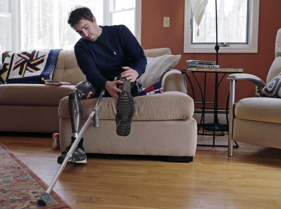 In this Friday, March 14, 2014 photo, Jeff Bauman adjusts one of his prosthetic legs at his home in Carlisle, Mass. Bauman, who lost both of his legs in the Boston Marathon bombings, helped identify one of the two brothers accused of setting off the explosions, which killed three and injured more that 260 others. (AP Photo/Charles Krupa)