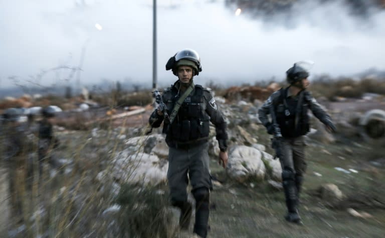 An Israeli border policeman looks on as he walks through tear gas fumes during clashes with Palestinian protesters near an Israeli checkpoint in the West Bank city of Ramallah on December 10, 2017