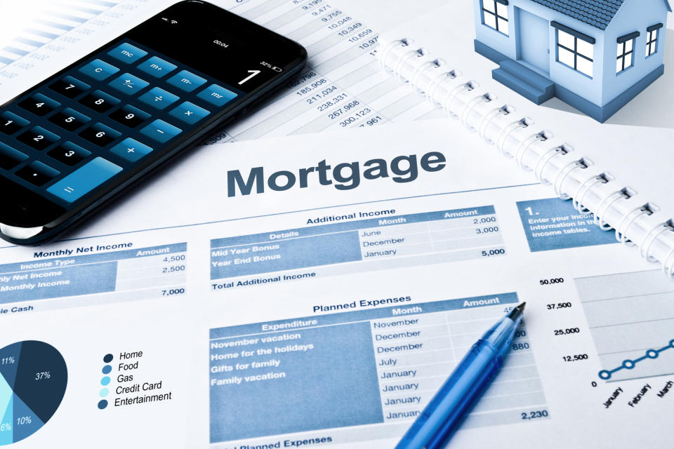 House miniature on financial documents with a calculator and pen, indicating mortgage budget planning