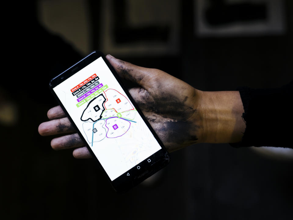 In this Oct. 23, 2019 photo, Maya, 19, a psychology student from Versailles holds her phone showing a map of Paris as she explains how the women of the movement divided Paris into five different pasting zones. Activists have pasted signs all over Paris to pressure authorities to do more to help victims of domestic violence, whom they say law enforcement too often fail to protect. (AP Photo/Kamil Zihnioglu)