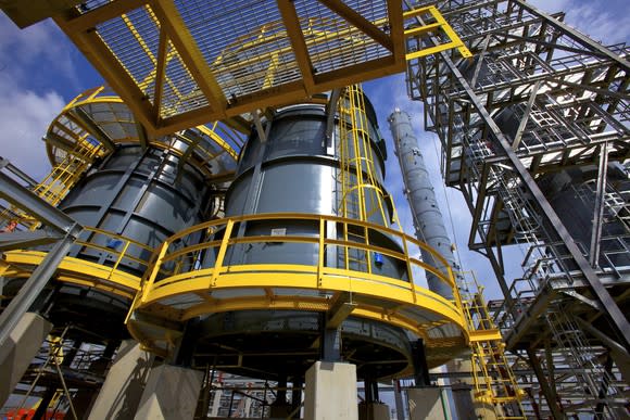 Extensive network of grey and yellow platforms and holding tanks at an energy facility.