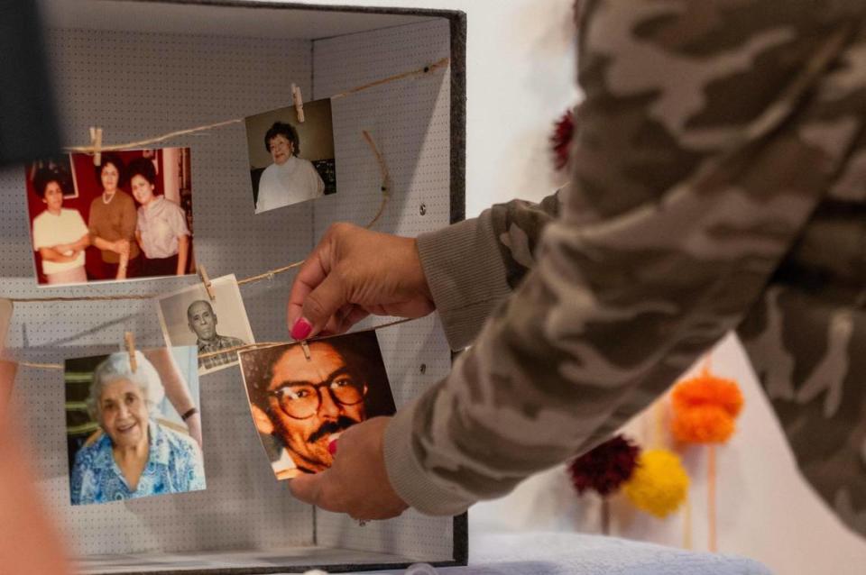 Liz Freeman clips family photographs in a shadow box to display on her family’s altar.