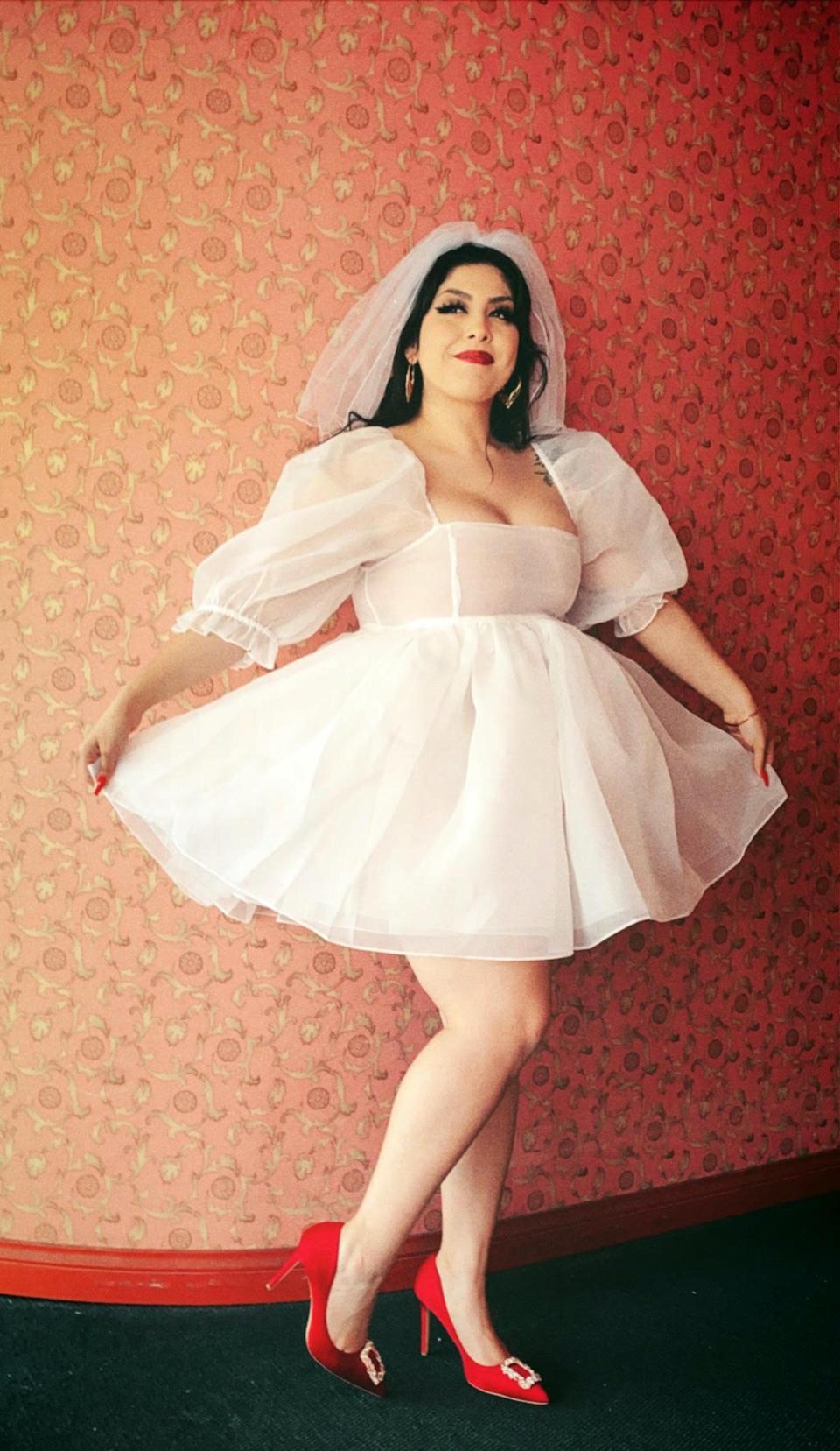 A bride poses in a white mini dress and matching veil.