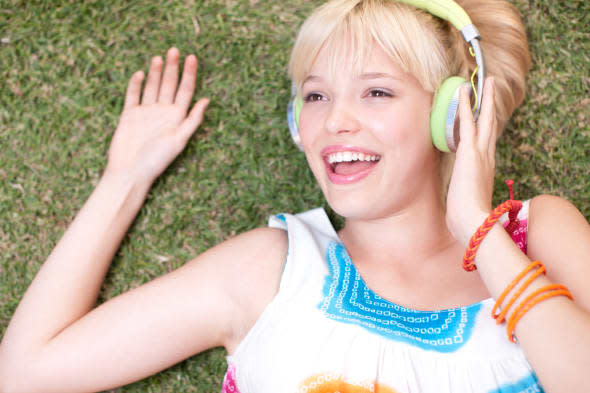 Woman laying on grass listening to headphones