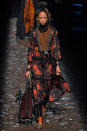 <p>Model wears an orange and black rose-print dress with a whipstitch and suede panel on the center of the dress. (Photo: Getty) </p>