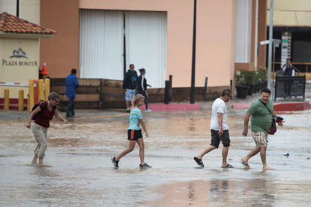 Tourists walk through a partially flooded street following the passing of Tropical Storm Lidia in Los Cabos, Mexico, August 31, 2017. REUTERS/Fernando Castillo