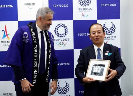 Paris 2024 Director General Etienne Thobois wearing a Japanese happi coat presents a photo of Japanese athletes taken at 1924 Paris Olympic Games to Toshiro Muto, Tokyo 2020 CEO, during a ceremony marking conclusion of MoU between Tokyo 2020 and Paris 2024 Olympic Games in Tokyo, Japan, July 11, 2018. REUTERS/Kim Kyung-Hoon