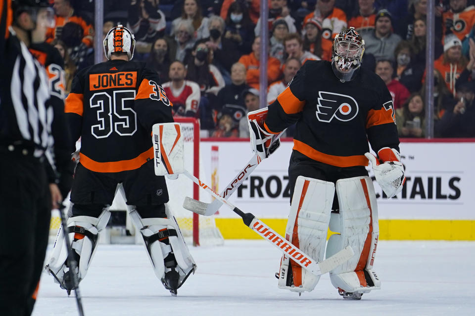 Philadelphia Flyers' Carter Hart, right, skates off the ice after being replaced by Philadelphia Flyers' Martin Jones during the second period of an NHL hockey game against the Tampa Bay Lightning, Sunday, Dec. 5, 2021, in Philadelphia. (AP Photo/Matt Slocum)