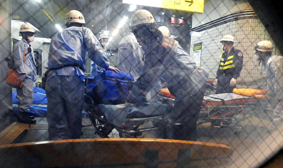 Rescuers papare stretchers at Soshigaya Okura Station after stabbing on a commuter train, in Tokyo Friday, Aug. 6, 2021. A man with a knife stabbed passengers on a commuter train Friday and was arrested by police after fleeing, fire department officials and news reports said. (Kyodo News via AP)