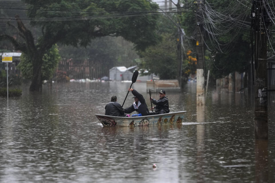 Residents row a boat in a flooded street after heavy rains, in Porto Alegre, Rio Grande do Sul state, Brazil, Saturday, May 11, 2024. (AP Photo/Andre Penner)