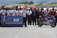 Teammates of 19 years-old Swiss pilot Jason Dupasquier stand near his motorbike, right, as they pay a minute of silence in his memory prior to the start of the Motogp Grand Prix of Italy at the Mugello circuit, in Scarperia, Italy, Sunday, May 30, 2021. Dupasquier died Sunday after being hospitalized Saturday, at the Florence hospital following his crash during the qualifying practices of the Moto3. (AP Photo/Antonio Calanni)
