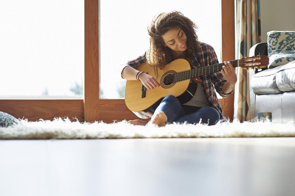 woman playing an acoustic guitar at home