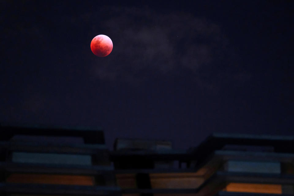 The moon rises over an apartment block.