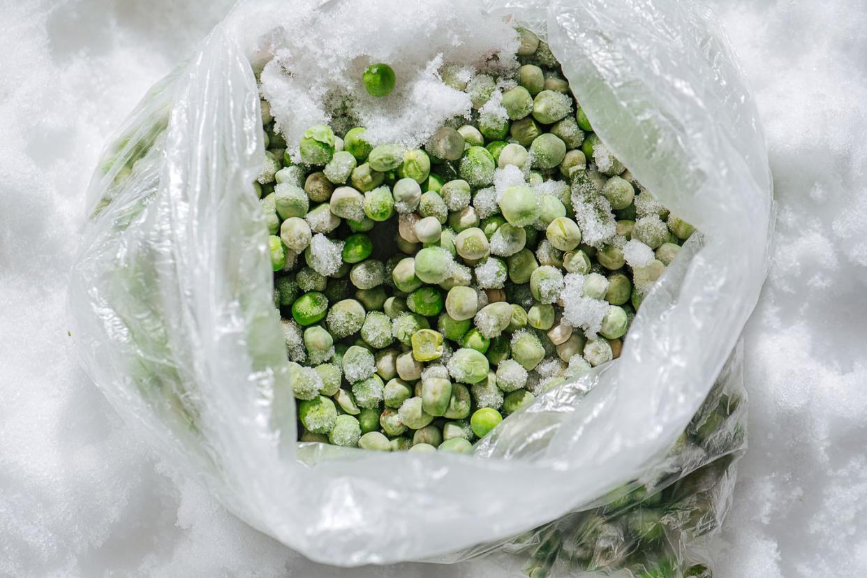 green frozen peas covered with tiny ice crystals in a plastic bag top view