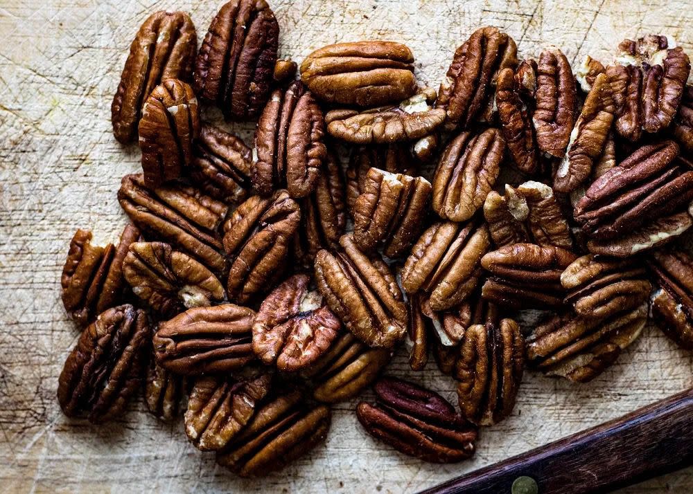 Pile of pecans on a textured light background.
