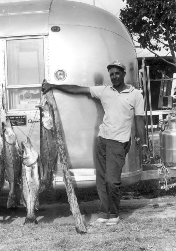 A man named Clair Conley proudly displays his string of snook.