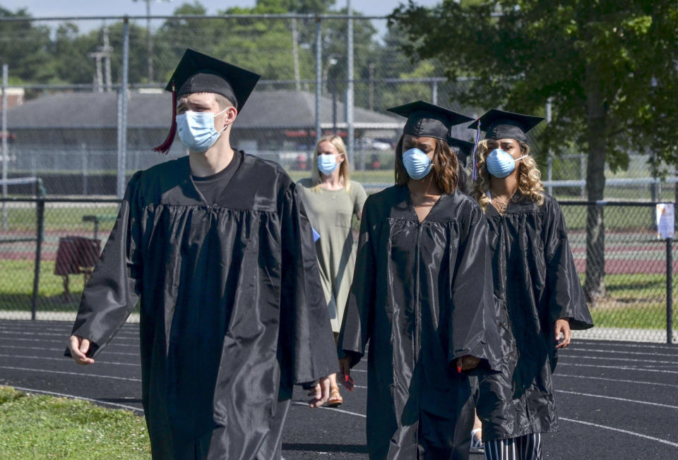 Members of the Vigo Virtual Success Academy class of 2020 make their way around the track at the start of their graduation ceremony at the Terre Haute South football field, Friday, July 17, 2020 in Terre Haute, Ind. (Austen Leake/The Tribune-Star via AP)