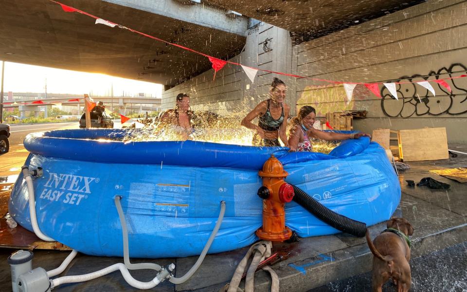 People hook a makeshift swimming pool up to a fire hydrant amid a heat wave in Portland - REUTERS 