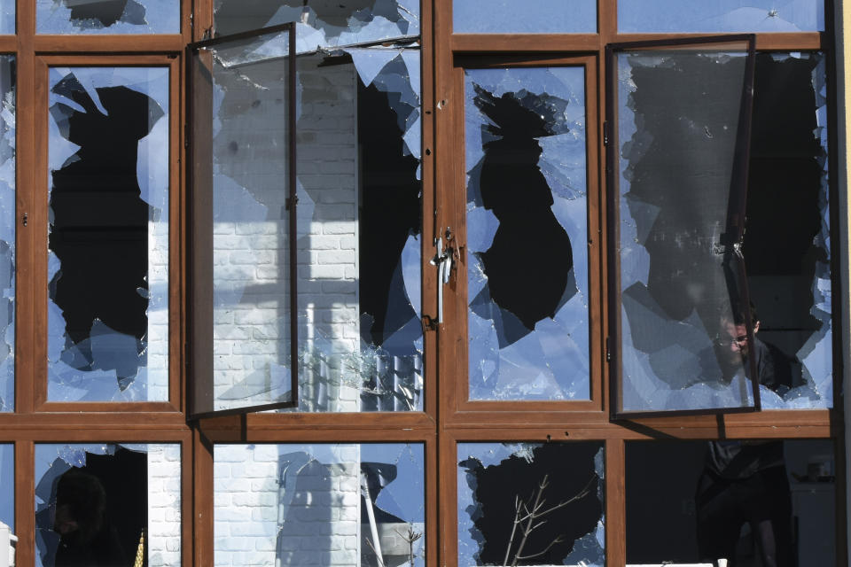 FILE - A man appears through shattered windows of a building after a shelling in Odesa, Ukraine, March 21, 2022. The Black Sea port is mining its beaches and rushing to defend itself from a Mariupol-style fate. Bombardment over the weekend led to fresh alarm. (AP Photo/Max Pshybyshevsky, File)
