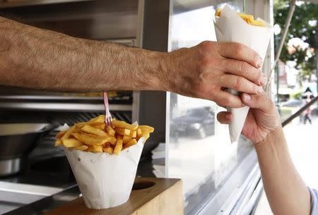 A customer buys a large cone of fries at Frit-Flagey, a popular frites stand in Brussels July 28, 2010. REUTERS/Francois Lenoir