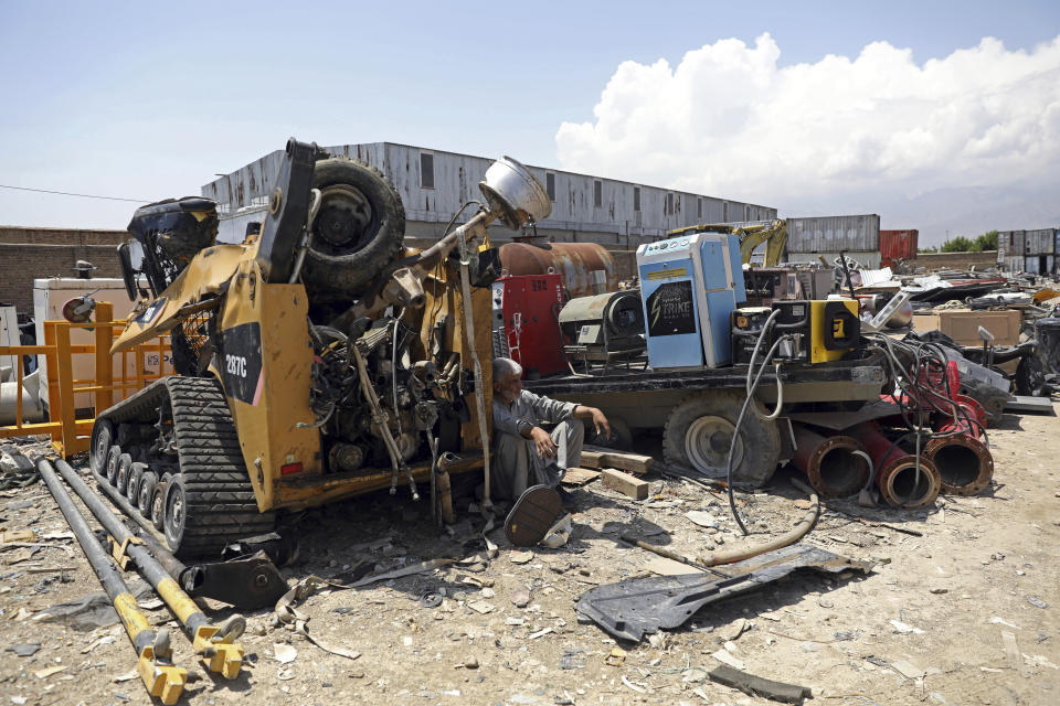 FILE - In this May 3, 2021 file photo, a man rests in the shade of destroyed machinery sold by the US military to a scrapyard, outside Bagram Air Base, in Afghanistan. In 2001 the armies of the world united behind America and Bagram Air Base, barely an hours drive from the Afghan capital Kabul, was chosen as the epicenter of Operation Enduring Freedom, as the assault on the Taliban rulers was dubbed. It’s now nearly 20 years later and the last US soldier is soon to depart the base. (AP Photo/Rahmat Gul, File)