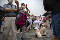Parents wearing face masks to protect against the coronavirus take photos of students as they pose for a group photo at the Temple of Heaven in Beijing, Saturday, July 18, 2020. Authorities in a city in far western China have reduced subways, buses and taxis and closed off some residential communities amid a new coronavirus outbreak, according to Chinese media reports. They also placed restrictions on people leaving the city, including a suspension of subway service to the airport. (AP Photo/Mark Schiefelbein)
