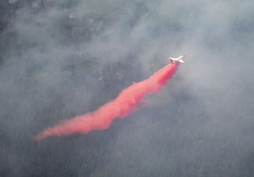 An aircraft drops red fire retardant onto the Greenwood Fire, about 50 miles north of Duluth, Minn., Tuesday, Aug. 17, 2021, as seen from an airplane above the temporary flight restriction zone. (Alex Korman/Star Tribune via AP)