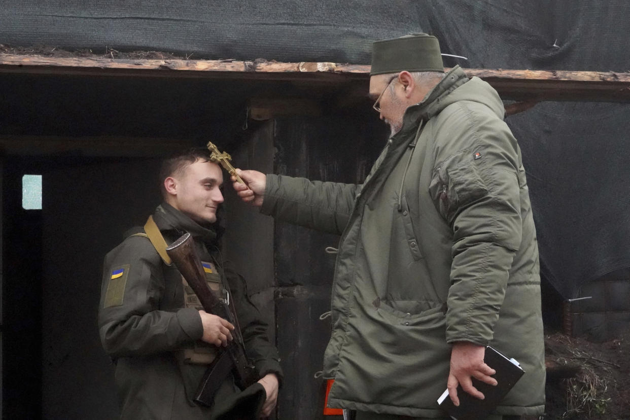 A chaplain blesses a soldier to mark Christmas at Ukraine's National Guard position close to the Russian border near Kharkiv, Ukraine, Saturday Dec. 24, 2022. (AP Photo/Andrii Marienko)