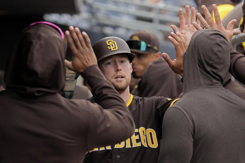 San Diego Padres' Jake Cronenworth celebrates with teammates after scoring on a double hit by Trent Grisham during the second inning of a spring training baseball game against the Texas Rangers Wednesday, March 1, 2023, in Peoria, Ariz. (AP Photo/Charlie Riedel)