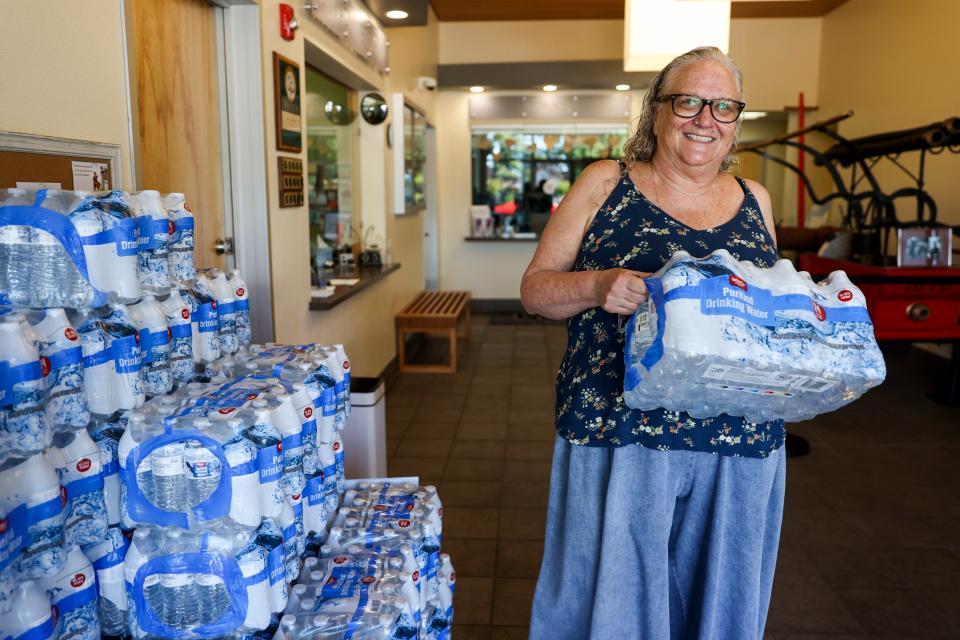 Cami Windsor carries a case of water Tuesday from Gervais City Hall.