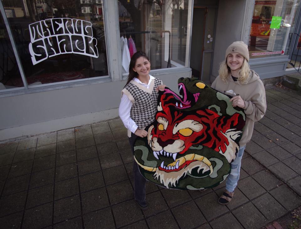 Megan Belmonte, left, and Matt Turner in front of their soon-to-be finished store in downtown Bridgewater, called The Rug Shack, on Thursday, Dec. 2, 2021. Turner is an artist who specializes in creating artistic rugs of a wide variety of designs, such as the tiger rug they are holding. Turner and Belmonte have been working to get the word out about the new shop, and heard from many other artists in the local area. Turner plans to expand the business where artists can come together and the location will also include a studio for podcasts.