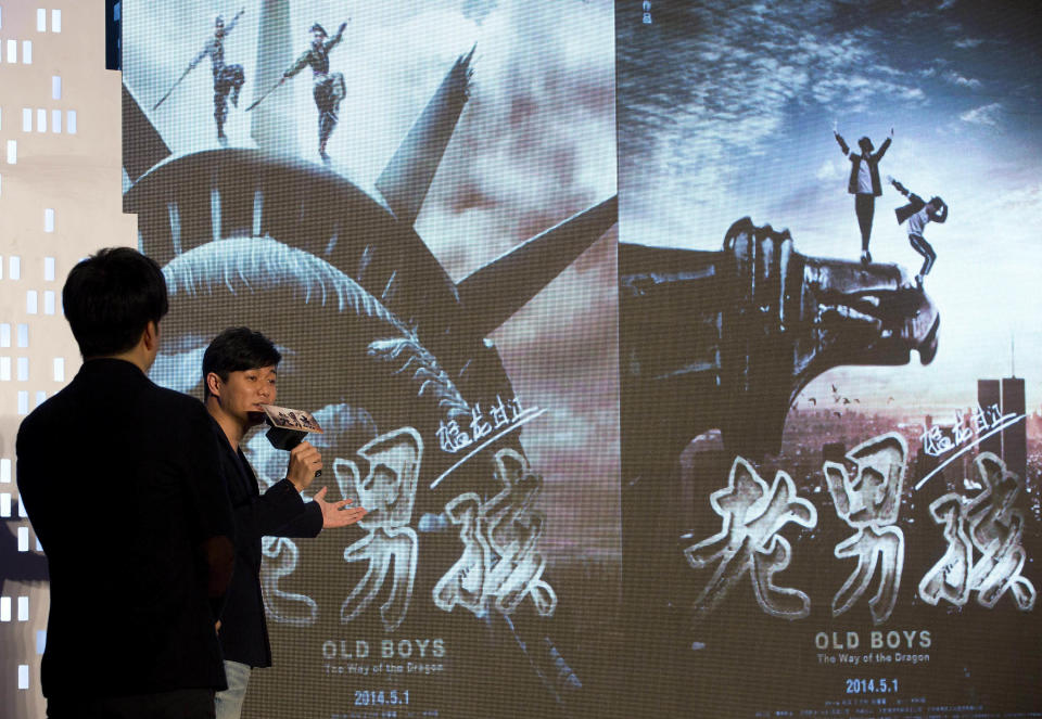 Chinese film director and actor Xiao Yang, right, and actor Wang Taili, left, speak on stage as they promote their new movie “Old Boys: The Way of the Dragon” in Beijing Thursday, Jan. 9, 2014. An online microfilm that was watched by millions and helped to establish a genre in China is to be made into a feature-length movie and shown in the country’s cinemas. The planned debut of “Old Boys” in China’s cinemas in May after ratcheting up almost 70 million views on a video website demonstrates how online films are influencing the traditional film industry. (AP Photo/Andy Wong)