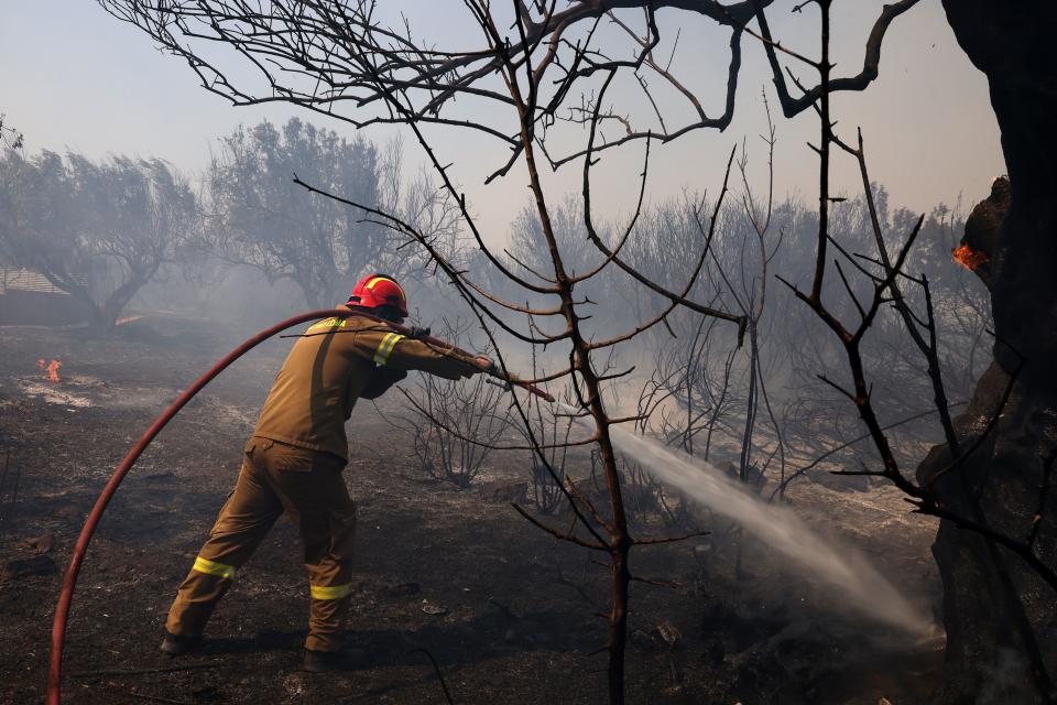 Firefighters extinguish a wildfire in Kitsi near the town of Koropi in Greece on Wednesday (Anadolu via Getty Images)