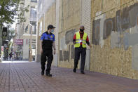 Two security officers walk in downtown Portland, Ore., Monday, July 13, 2020, alongside an entire block of shop windows that have been boarded up following nightly protests that have been going on for seven weeks. Violent clashes between protesters and police have divided the liberal city, paralyzed the downtown and attracted the attention of President Donald Trump, who sent federal law enforcement to the city to quell protests. (AP Photo/Gillian Flaccus)