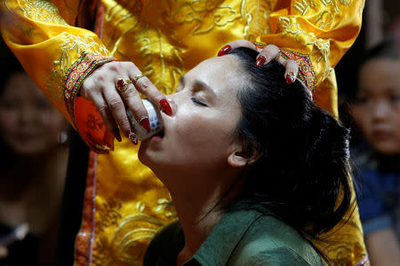 Pham Thi Thanh drinks a glass of water used as a treatment during a medium ritual at a Hau Dong ceremony at Phu Day temple in Nam Dinh province, Vietnam, May 7, 2017. REUTERS/Kham