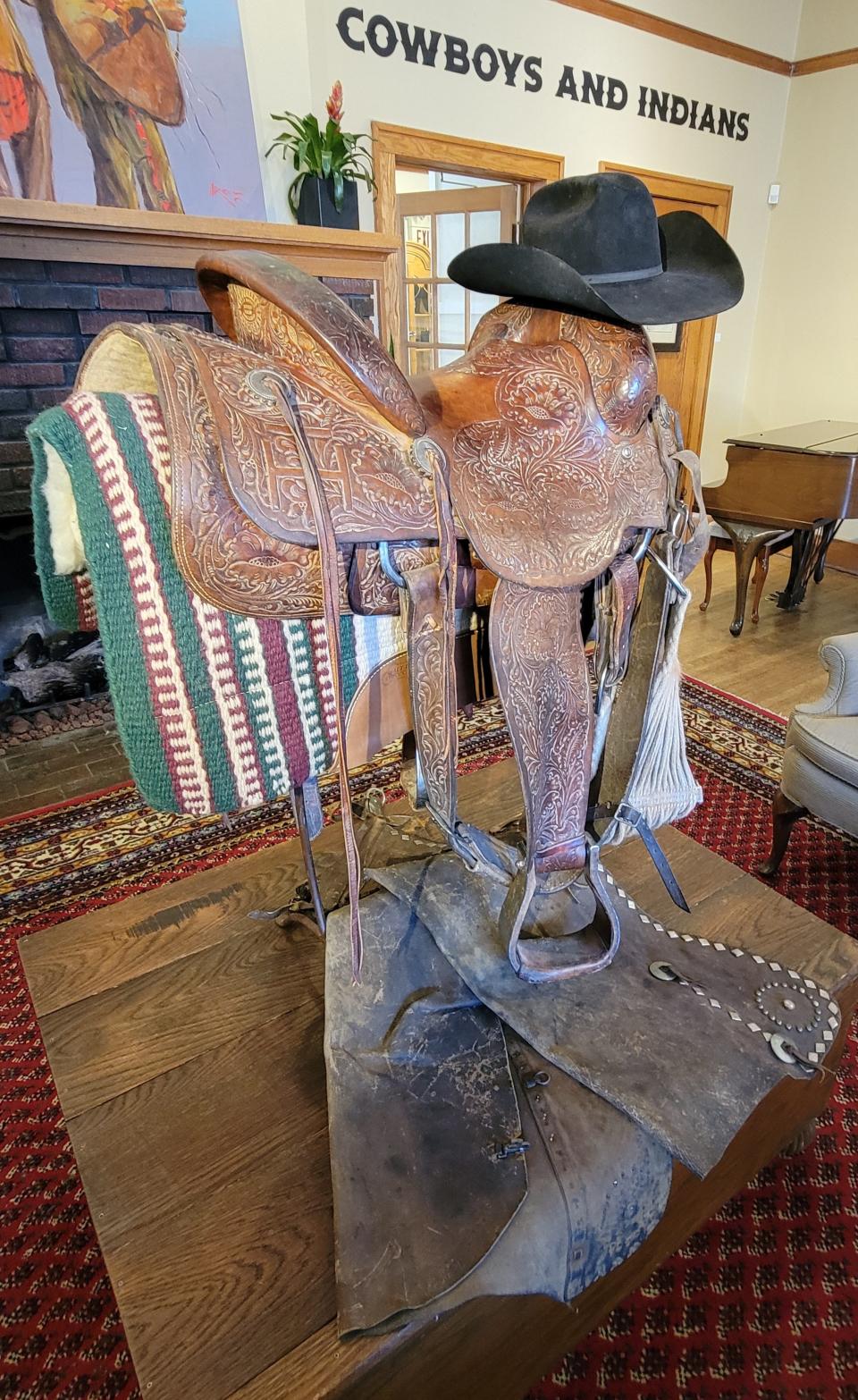 A saddle, cowboy hat and chaps that belonged to the late Harold T. Holden are displayed at JRB Art at the Elms gallery in Oklahoma City's Paseo Arts District Feb. 1, 2024. The exhibit "Cowboys and Indians," featuring works by Oklahoma artists Holden, Larsen and Jack Fowler, is on view through Feb. 29. Holden died Dec. 6, 2023, at the age of 83.