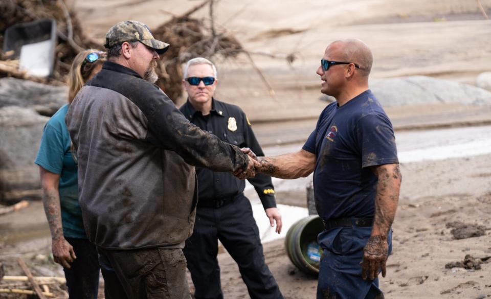 Don Stinson thanks firefighter Jason Trevino for pulling him from deep mud as Battalion Chief Jason Sultzer looks on