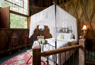 <p>The second-floor bedroom has a canopied queen bed. (Airbnb) </p>