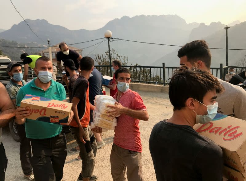 Volunteers unload humanitarian aid to be distributed to people affected by the wildfires in Ait Daoud village