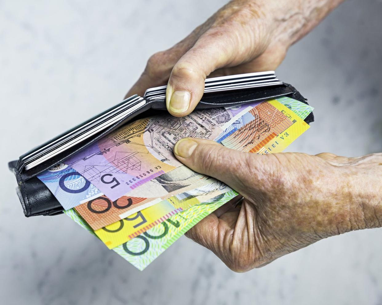 senior hands holding foreign currency