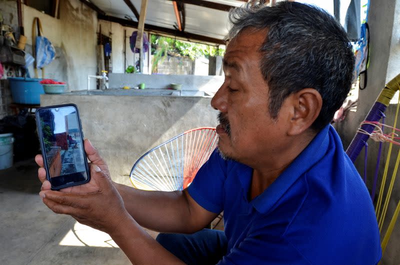 Gerardo Zacarias, who fears his daughter Paola Damaris is among the 19 bodies found shot and burnt in a remote part of northern Mexico, watches the news on his cell phone, in Catarina