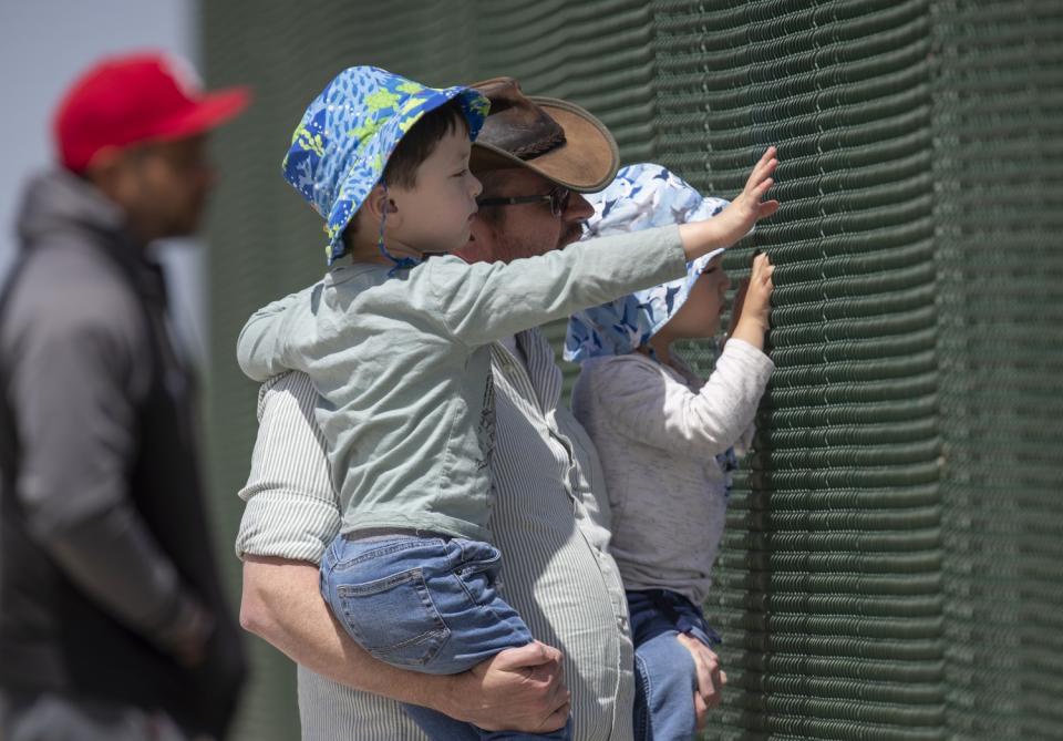 David Galazyn and his sons, Clark, 4, left, and Lewis, 2, peer through the fence at the Walnut Avenue overpass of the 55.