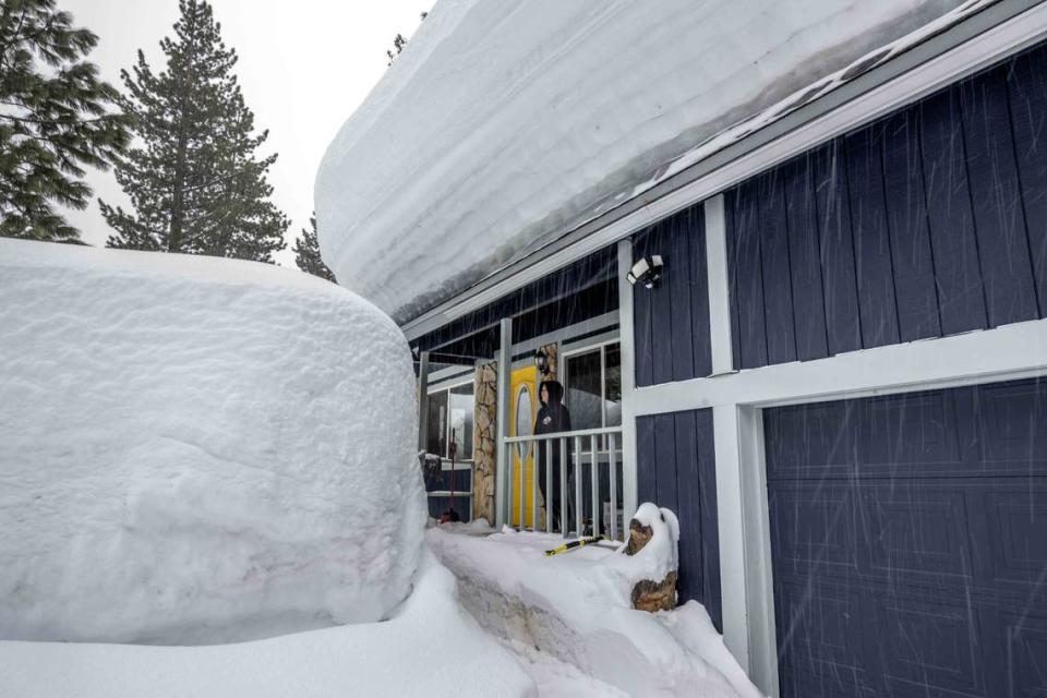 Erika Travillion of South Lake Tahoe stands in front of her home as snow falls on Monday, March 6, 2023 in El Dorado County. Only a light dusting is expected at elevations around 6,000 feet this week.