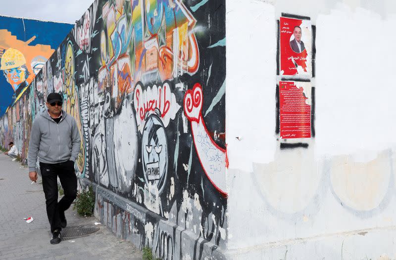 A man walks near campaign posters ahead of the parliamentary election in Tunis