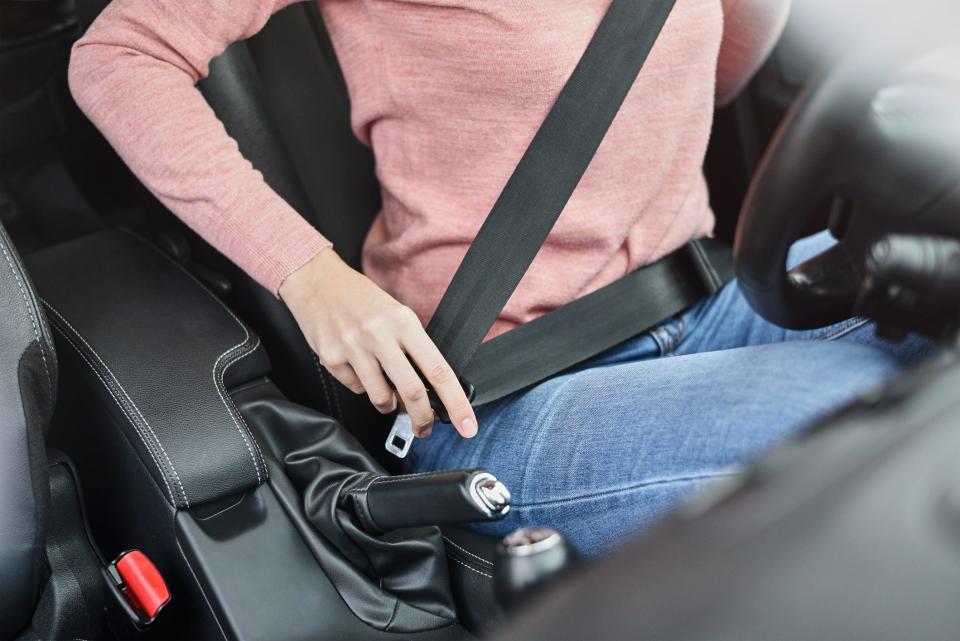Woman fastening seat belt in car.