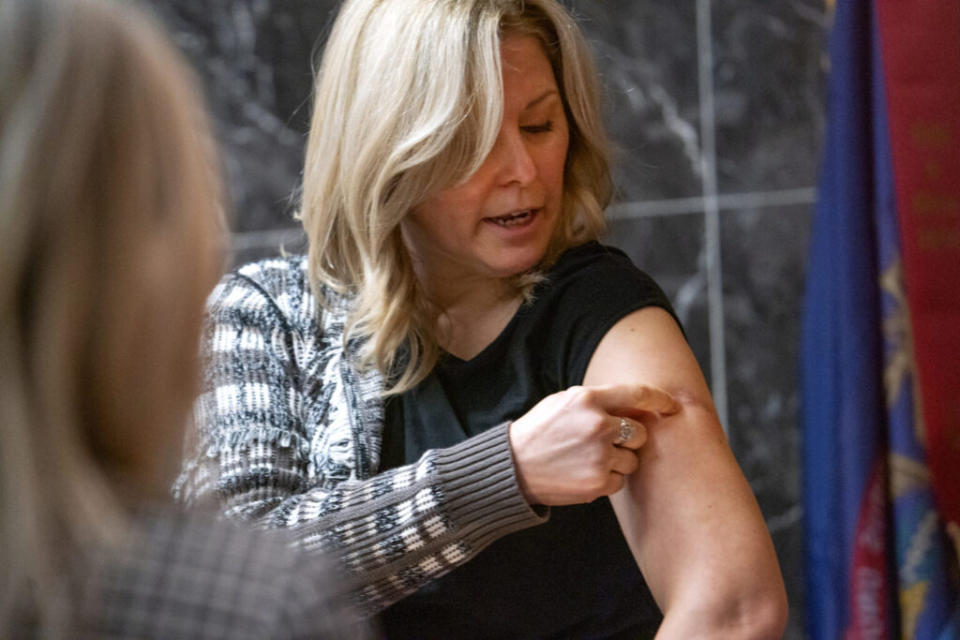 A woman showing a scar caused by a bullet