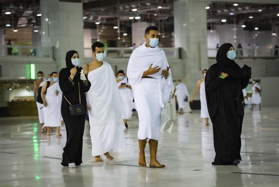 CLARIFIES THAT THE UMRAH PILGRIMAGE CAN BE UNDERTAKEN AT ANY TIME OF THE YEAR -- In this photo released by Saudi Ministry of Hajj and Umrah, Muslims practice social distancing while praying around the Kaaba, the cubic building at the Grand Mosque during the first day umrah pilgrimages were allowed to restart, in the Muslim holy city of Mecca, Saudi Arabia, Sunday, Oct. 4, 2020. The umrah pilgrimage, or smaller pilgrimage, can be undertaken at any time of the year. A very small, limited number of people donning the white terrycloth garment symbolic of the Muslim pilgrimage circled Islam's holiest site in Mecca on Sunday after Saudi Arabia lifted coronavirus restrictions that had been in place for months. (Saudi Ministry of Hajj and Umrah via AP)