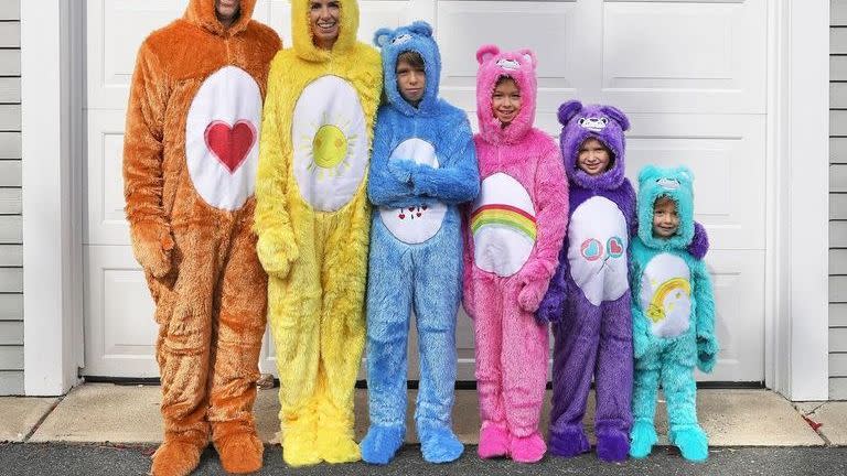 family of 6 wearing care bears onesies for group 80s costume standing from tallest to shortest